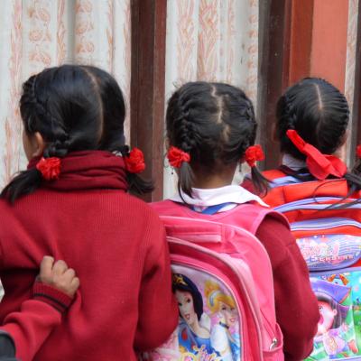 Students in Nepal wait patiently in a line for their Childcare volunteer Children line up with their backpacks outside their classroom in Nepal